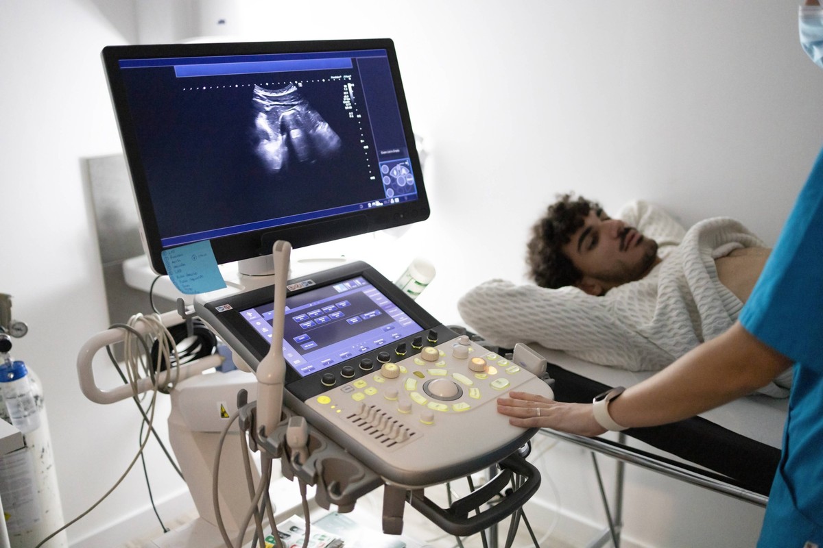 A patient lies on an examination table receiving an ultrasound scan with a sonographer operating the equipment. Model Released DavidMunoz_ID19657_582910_043 Copyright: xDavidxMunozx