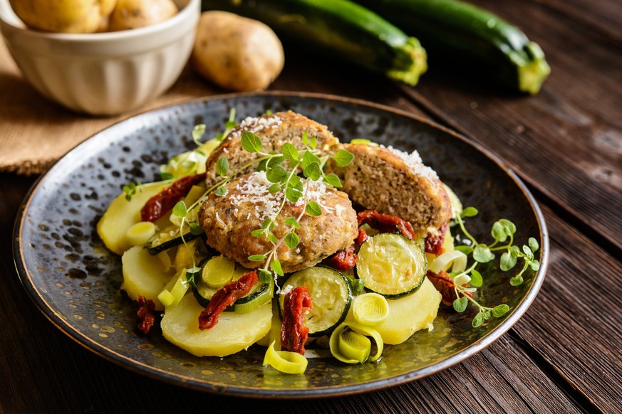 Fried minced pork patties meat with steamed potato, zucchini, leek and sun dried tomato