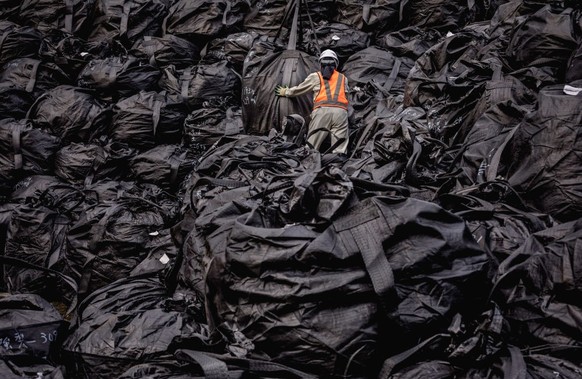 FUKUSHIMA, OKUMA, JAPAN - 2019/09/20: Radioactive soil has been decontaminated from the land around Fukushima and packed in black bags that are stacked on piles while waiting to be transported to the  ...