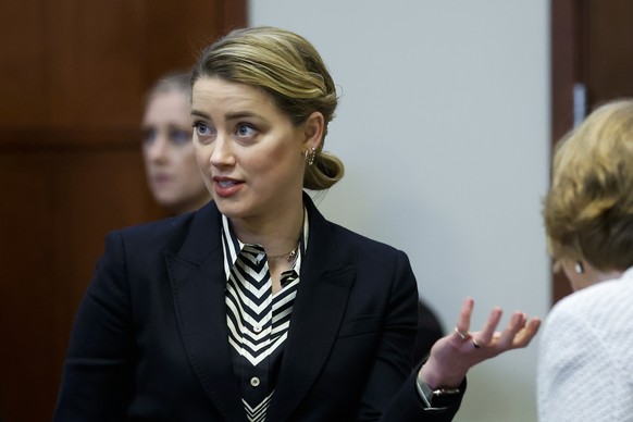 Actor Amber Heard speaks to her legal team in the courtroom at the Fairfax County Circuit Court in Fairfax, Va., Wednesday, April 27, 2022. Actor Johnny Depp sued his ex-wife actress Amber Heard for l ...