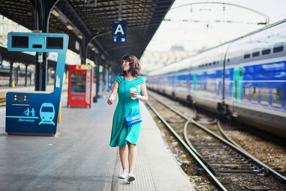 Young woman in Paris waiting for a train on railway station. Local French commuter going to work or vacation. Tourist using subway or intercity train in France