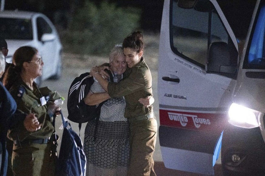 Margalit Mozes, a released Israeli hostage, walks with an Israeli soldier shortly after her arrival in Israel on Friday, Nov. 24, 2023. A four-day cease-fire in the Israel-Hamas war began in Gaza on F ...