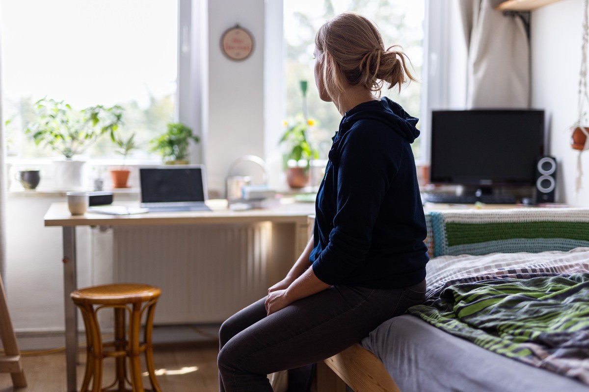 ARCHIV - 13.08.2023, Niedersachsen, Hannover: Eine Studentin sitzt auf dem Bett in ihrem WG-Zimmer und schaut aus dem Fenster (gestellte Szene). (zu dpa: «Wege aus der Einsamkeit») Foto: Michael Matth ...