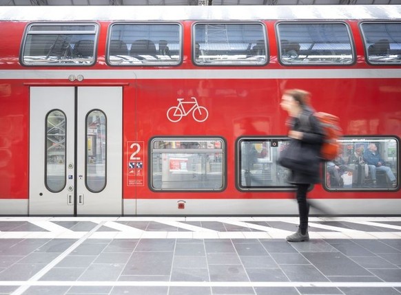 ARCHIV - 01.05.2023, Hessen, Frankfurt/Main: Eine Frau geht am Frankfurter Hauptbahnhof an einer Regionalbahn vorbei. (Zu dpa &quot;Verbund zieht nach einem Monat Deutschlandticket positive Bilanz&quo ...