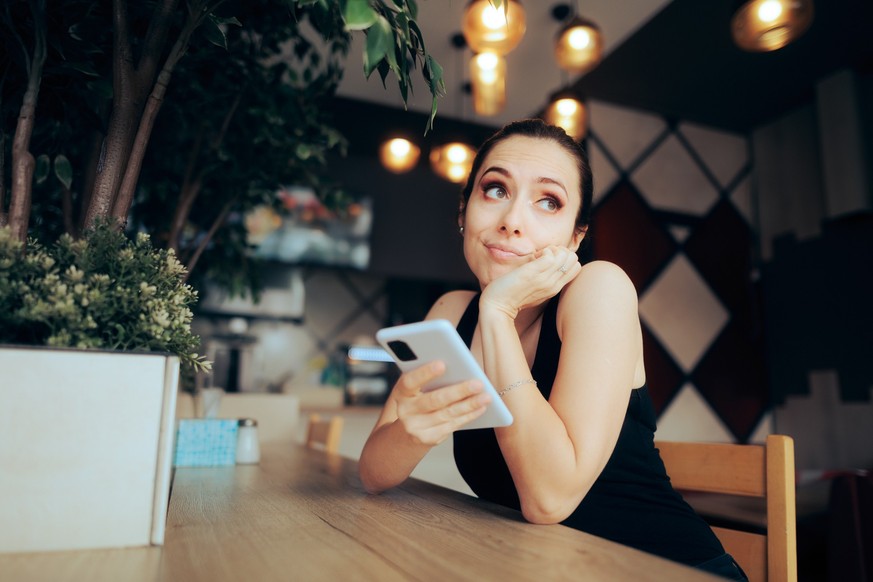 Funny girl feeling bored using a dating app while waiting food order