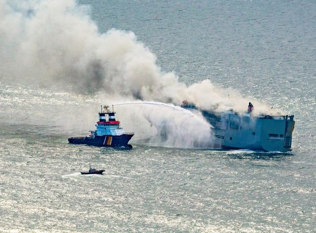 26.07.2023, Niederlande, Ameland: Eine Luftaufnahme zeigt den deutschen Notschlepper &quot;Nordic&quot; (l), der das Feuer auf einem brennenden Frachter in der Nordsee bekämpft. Wie die niederländisch ...