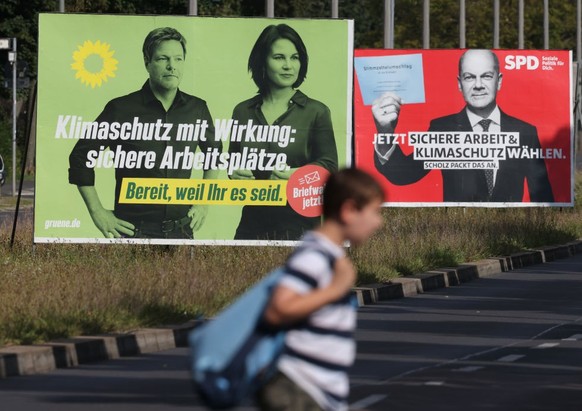 BERLIN, GERMANY - AUGUST 24: A boy walks past election campaign billboards showing Robert Habeck and chancellor candidate Annalena Baerbock of the German Greens Party (L) and Olaf Scholz, chancellor c ...