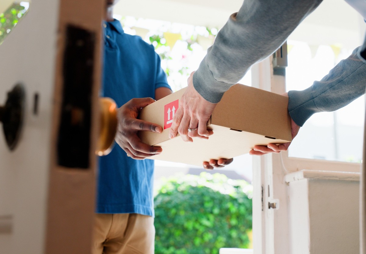 Hands, box and delivery man at front door in home with client, services and shipping for commercial product. People, courier and cardboard package for supply chain, logistics or distribution at house