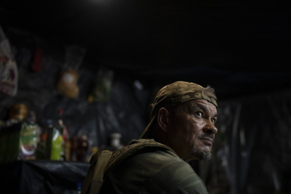 A Ukrainian soldier sits inside a trench on the frontline in the outskirts of Lyman, Ukraine, Tuesday, Aug. 15, 2023. (AP Photo/Bram Janssen)