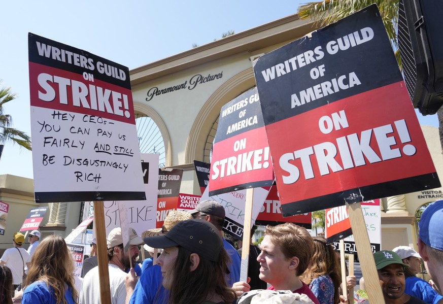 18.05.2023, USA, Los Angeles: Streikende Mitglieder der Writers Guild halten Schilder während einer Kundgebung vor dem Paramount Pictures Studio. In Hollywood hat die Gewerkschaft der Drehbuchautoren  ...