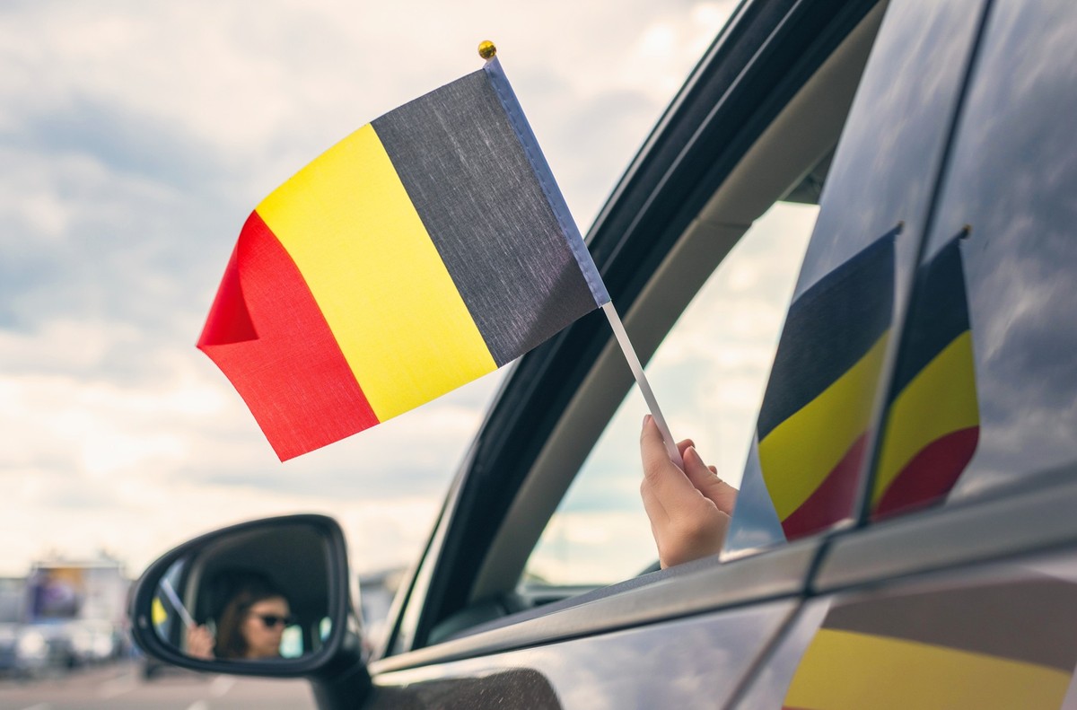 Woman or Girl Holding Belgian Flag from the open car window. Concept