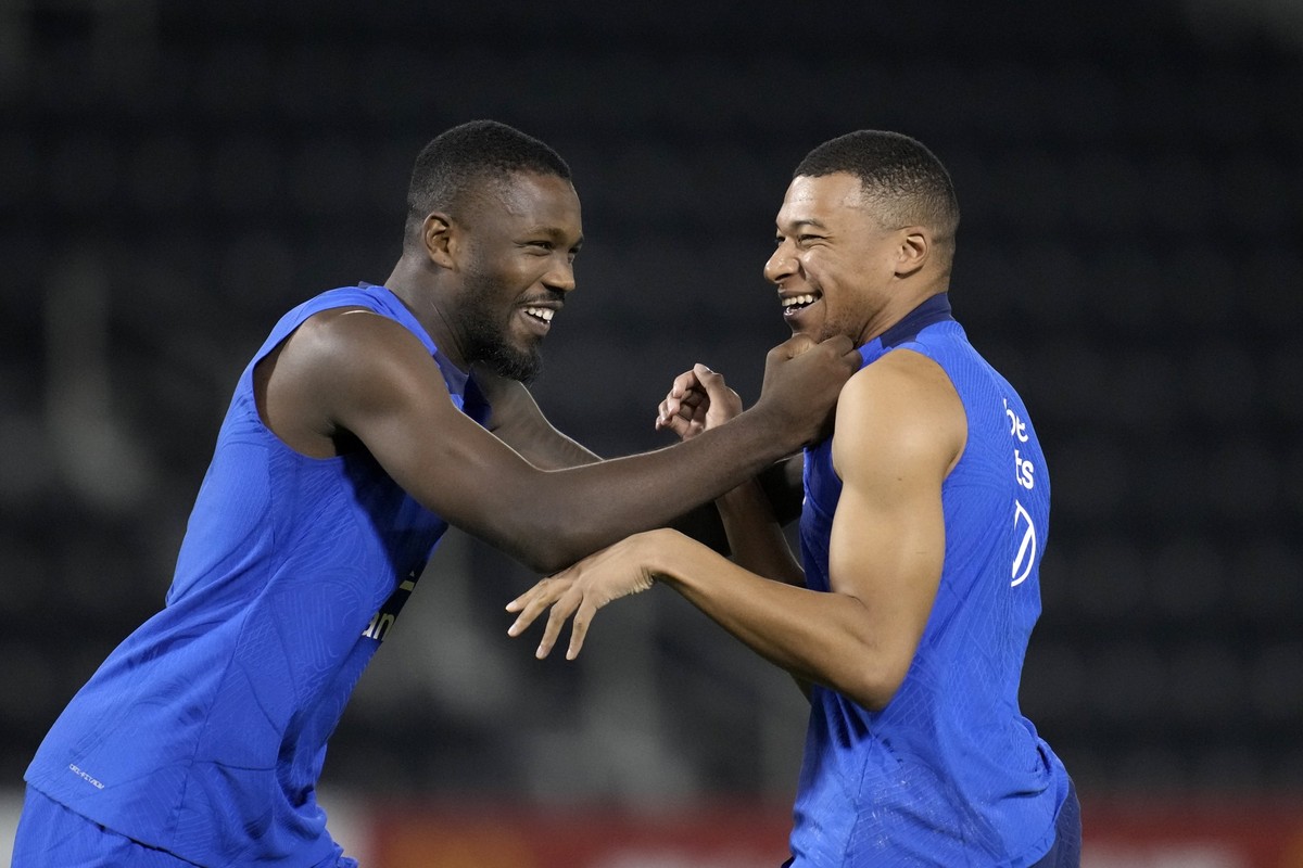 Marcus Thuram, left, and Kylian Mbappe joke during a training session at the Jassim Bin Hamad stadium in Doha, Qatar, Sunday, Nov. 20, 2022. France will play their first match in the World Cup against ...