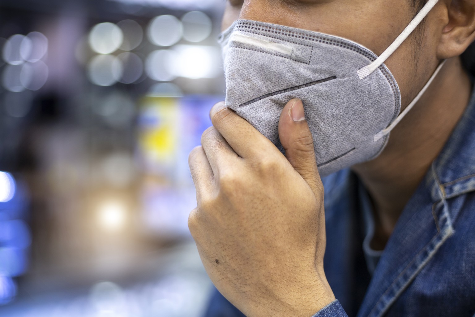 Close up portrait of a man using pm 2.5 pollution mask in the street of a big city