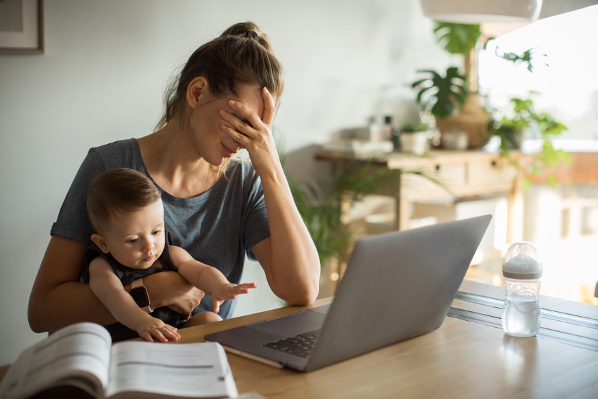 Mother and son sitting at the table with laptop. Mother is consulting online. Looking sad and frustrated.