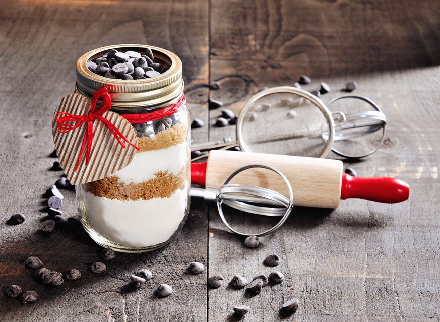 Chocolate chips cookie mix in a glass jar. St. Valentines day gift concept. Toned image, selective focus