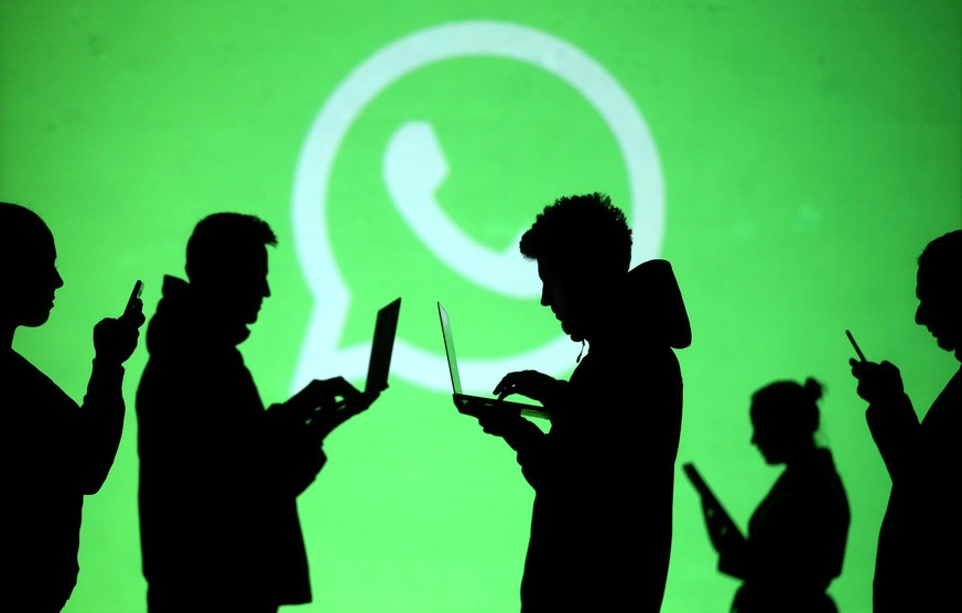 FILE PHOTO: Silhouettes of laptop and mobile device users are seen next to a screen projection of Whatsapp logo in this picture illustration taken March 28, 2018. REUTERS/Dado Ruvic/File Photo