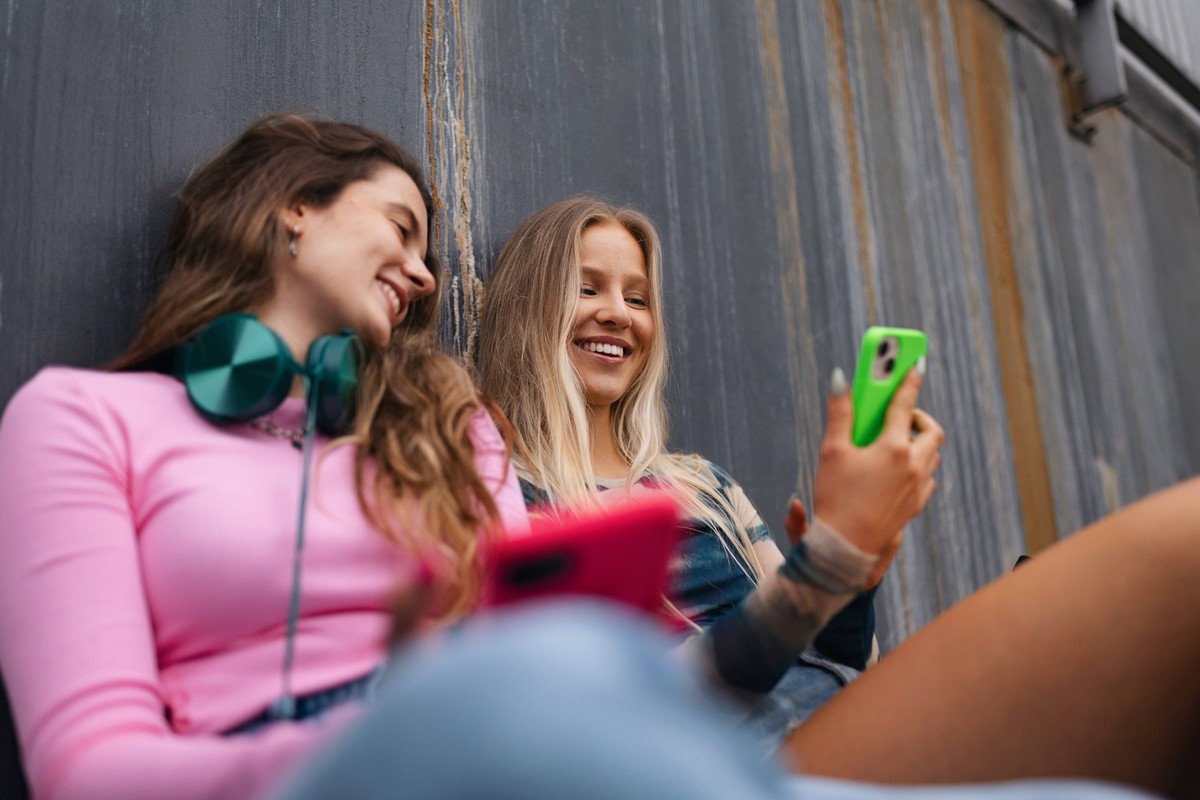 Young stylish generation Z girls spending time together outdoors after school. Young stylish generation Z girls spending time together outdoors after school. Young female zoomers talking and gossiping ...