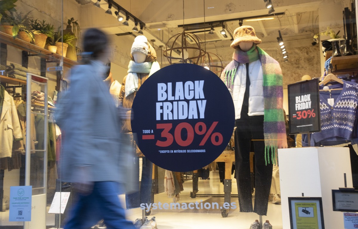 25.11.2022, Spanien, Palma: Eine Frau geht am Black Friday in der Innenstadt von Palma auf Mallora an einem Geschäft vorbei. Eine Flut von Sonderangeboten wenige Wochen vor Weihnachten, dadurch ist de ...