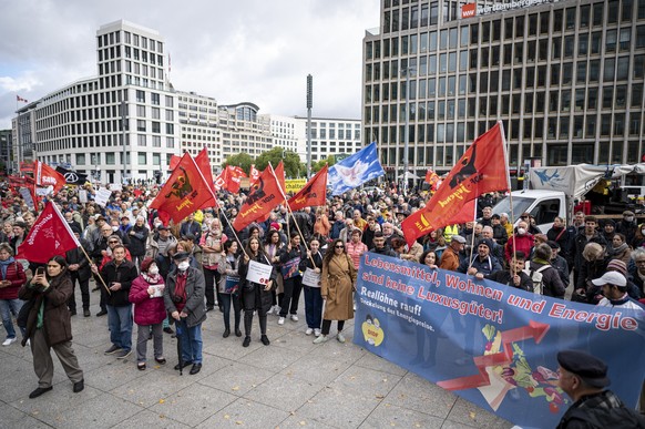 03.10.2022, Berlin: Teilnehmer stehen auf der Demonstration «Heizung, Brot & Frieden! Protestieren statt frieren» am Potsdamer Platz mit Fahnen und Plakaten. Die Demo wird von einem Bündnis versch ...