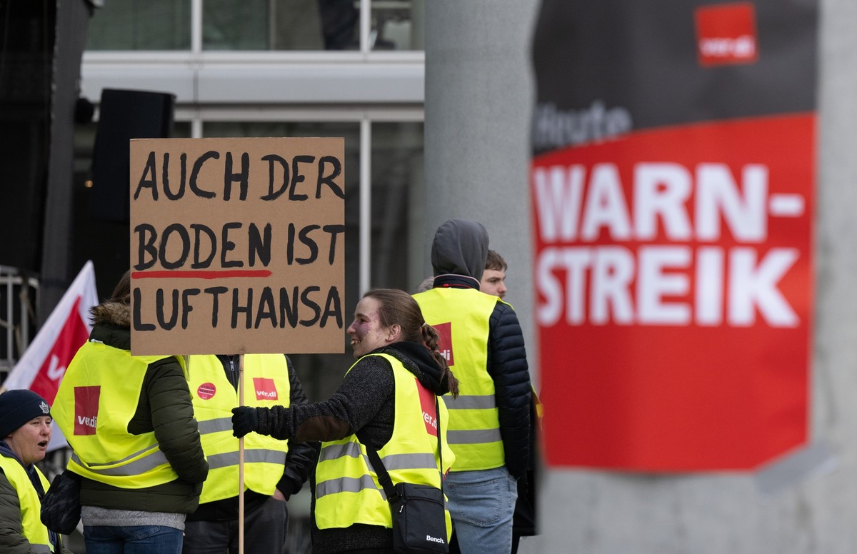 20.02.2024, Hessen, Frankfurt/Main: &quot;Auch der Boden ist Lufthansa&quot; steht auf einem Plakat, mit dem sich eine Frau am Streik beteiligt. Die Gewerkschaft Verdi hat das Lufthansa-Bodenpersonal  ...