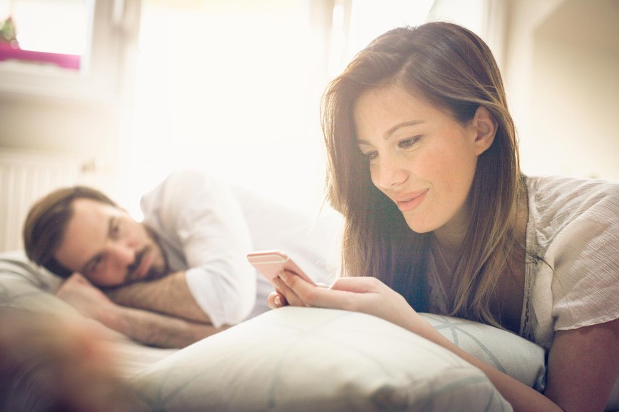 Young couple in bed. Focus on woman. Space for copy.