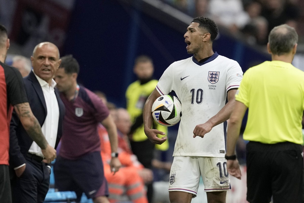 England&#039;s Jude Bellingham holds the ball next to Slovakia&#039;s head coach Francesco Calzona during a round of sixteen match between England and Slovakia at the Euro 2024 soccer tournament in Ge ...