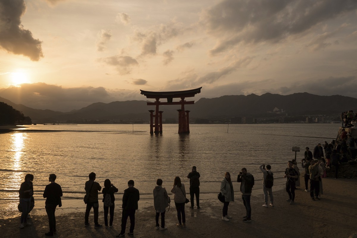 IMAGE DISTRIBUTED FOR HIROSHIMA TOURISM ASSOCIATION - Visitors watch the sunset in front of the Grand Torii Gate of the Itsukushima Shinto Shrine in Hatsukaichi City on Miyajima Island, Hiroshima, wes ...