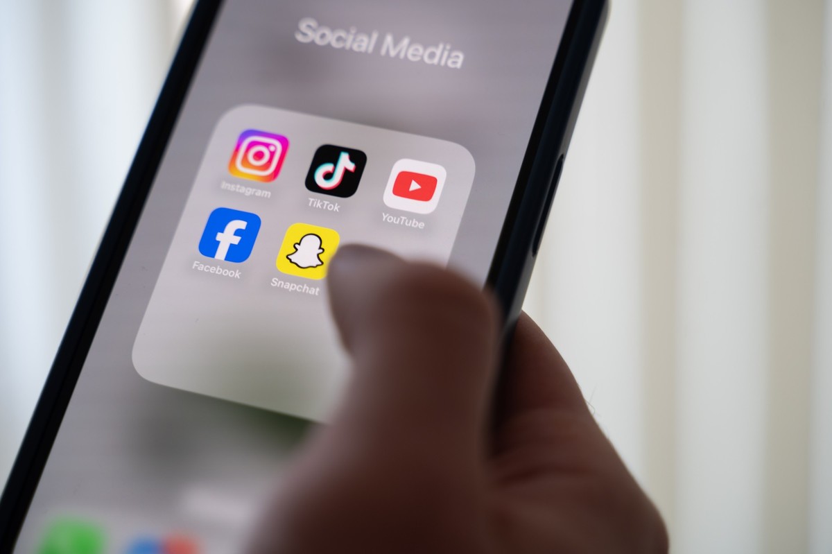 PRODUKTION - 24.10.2024, Niedersachsen, Hannover: ILLUSTRATION - Eine Frau h�lt ein Smartphone, auf dessen Display verschiedene Social Media Apps angezeigt werden. (zu dpa: �Polizei r�ckt wegen Tiktok ...