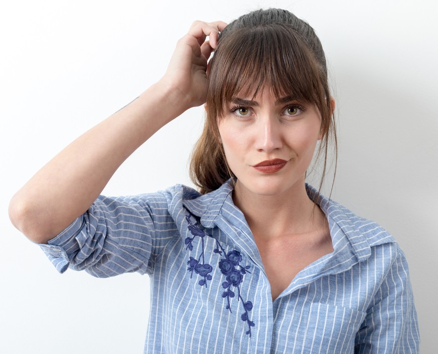 Confused young woman scratching head