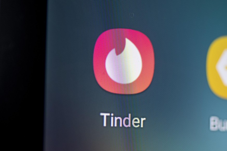 Auf dem Bildschirm eines Smartphones sieht man das Logo der Mobile-Dating-App Tinder.