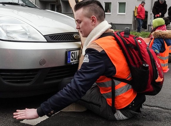 03.02.2023, Nordrhein-Westfalen, Köln: Aktivisten der Umweltgruppe «Letzte Generation» blockieren den Verkehr auf der Universitätsstraße indem sie ihre Hände auf der Fahrbahn festkleben. Mitglieder de ...