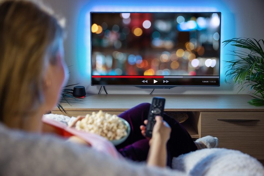 Female relaxing at home in evening and watching TV