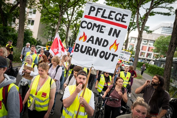 01.06.2022, Nordrhein-Westfalen, K�ln: Mit einem Plakat &quot;Pflege - come in and burn out&quot; nehmen Pflegekr�fte an einer Demonstration teil. Einen Monat dauern die Streiks der Besch�ftigten an s ...