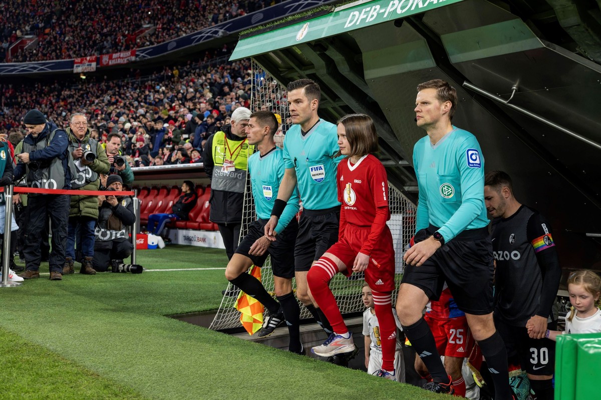 Harm Osmers betritt vor dem Pokalspiel zwischen Bayern und Freiburg mit seinem Schiedsrichter-Gespann den Rasen.