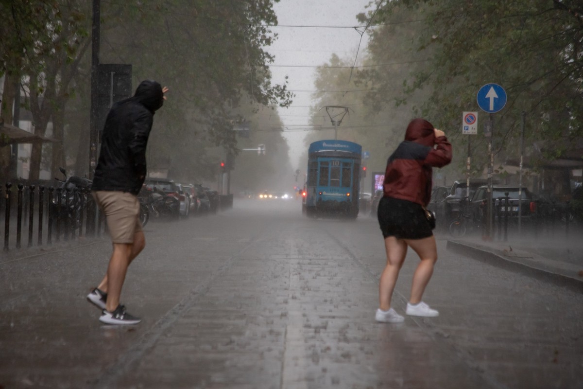 23.09.2023, Italien, Mailand: Ein Bürger schützt sich bei einem Gang über die Straße mit einem Regenschirm vor dem starken Regen. Foto: Claudio Furlan/LaPresse via ZUMA Press/dpa +++ dpa-Bildfunk +++