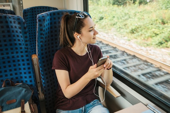 A young girl listens to a music or podcast while traveling in a train.