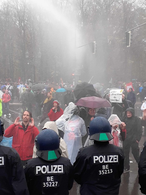 Die Demonstranten schützen sich mit Schirmen und Regenjacken.