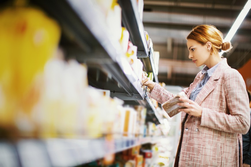 Young woman buying gluten free bread at supermarket.