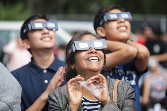 14.10.2023, Mexiko, Mexiko-Stadt: Menschen beobachten mit speziellen Schutzbrillen ausgestattet eine Sonnenfinsternis. Millionen Menschen in Teilen von Nord-, S�d- und Mittelamerika haben am Samstag e ...