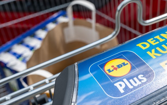 ILLUSTRATION - 15.05.2023, Sachsen, Leipzig: Ein Einkaufswagen mit dem Logo des Discounters Lidl steht am Kofferraum eines PKW in Leipzig. Der Discounter feiert jetzt seinen 50. Geburtstag. In Ludwigs ...