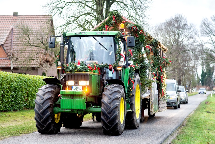 24.12.2020, Niedersachsen, Stuhr: Robert Vetter, Pastor der evangelischen Kirchengemeinde Stuhr, kommt an Heiligabend mit einem Traktor und Anhänger in die Ortschaft Blocken, um dort einen Gottesdiens ...