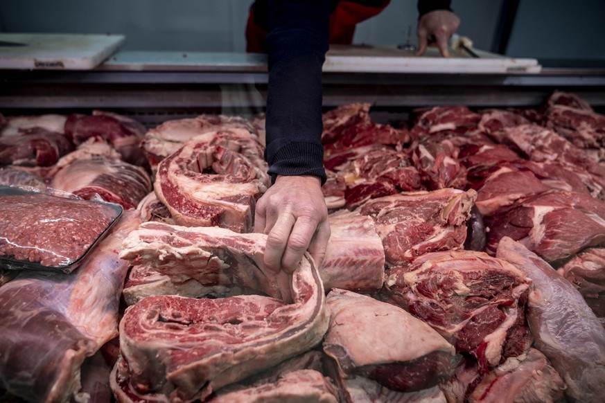 Variety of fresh meat at the butcher&#039;s shop and unrecognizable man grabbing a piece - Raw food