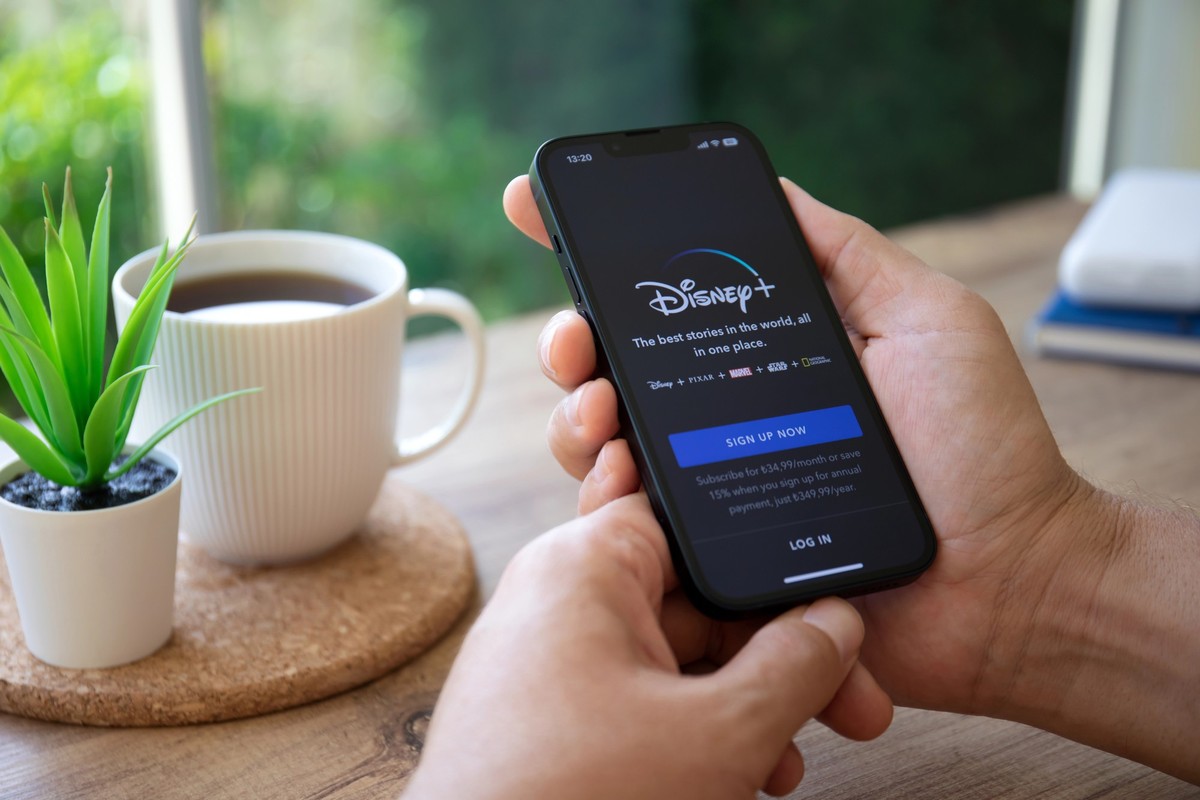 Alanya, Turkey - September 29, 2022: Man hands holding Apple iPhone 14 with multinational entertainment company Disney plus provides streaming media and video on the screen.