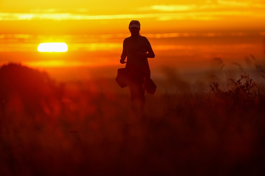 17.09.2023, Baden-Württemberg, Unlingen: Eine Frau joggt am Morgen auf einem Weg, während im die Sonne auf geht. Foto: Thomas Warnack/dpa +++ dpa-Bildfunk +++