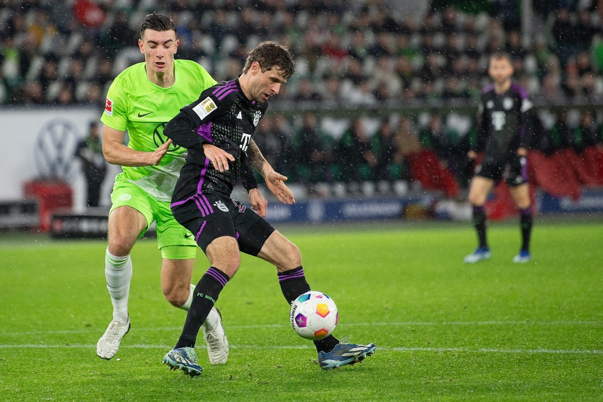 20.12.2023, Niedersachsen, Wolfsburg: Fußball: Bundesliga, VfL Wolfsburg - Bayern München, 16. Spieltag, Volkswagen Arena. Münchens Thomas Müller (r) spielt gegen Wolfsburgs Cedric Zesiger. Foto: Swen ...