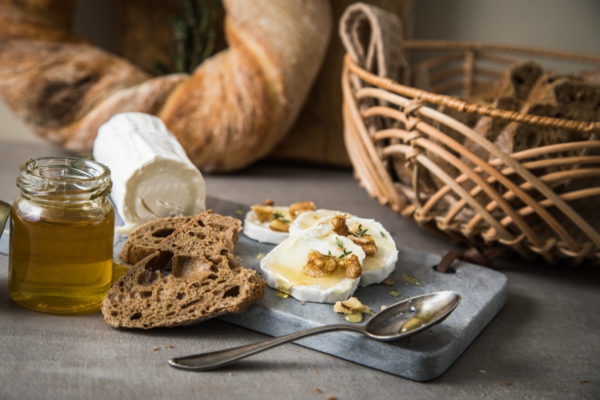 ILLUSTRATION - Ein gereifter Ziegenkäse mit Weißschimmel wird zusammen mit Honig, Thymianflocken und Walnüssen zu einer kompletten Vor- oder Nachspeise. (zu dpa: «Sag Cheese! Warum Käse auch zu Kaffee ...