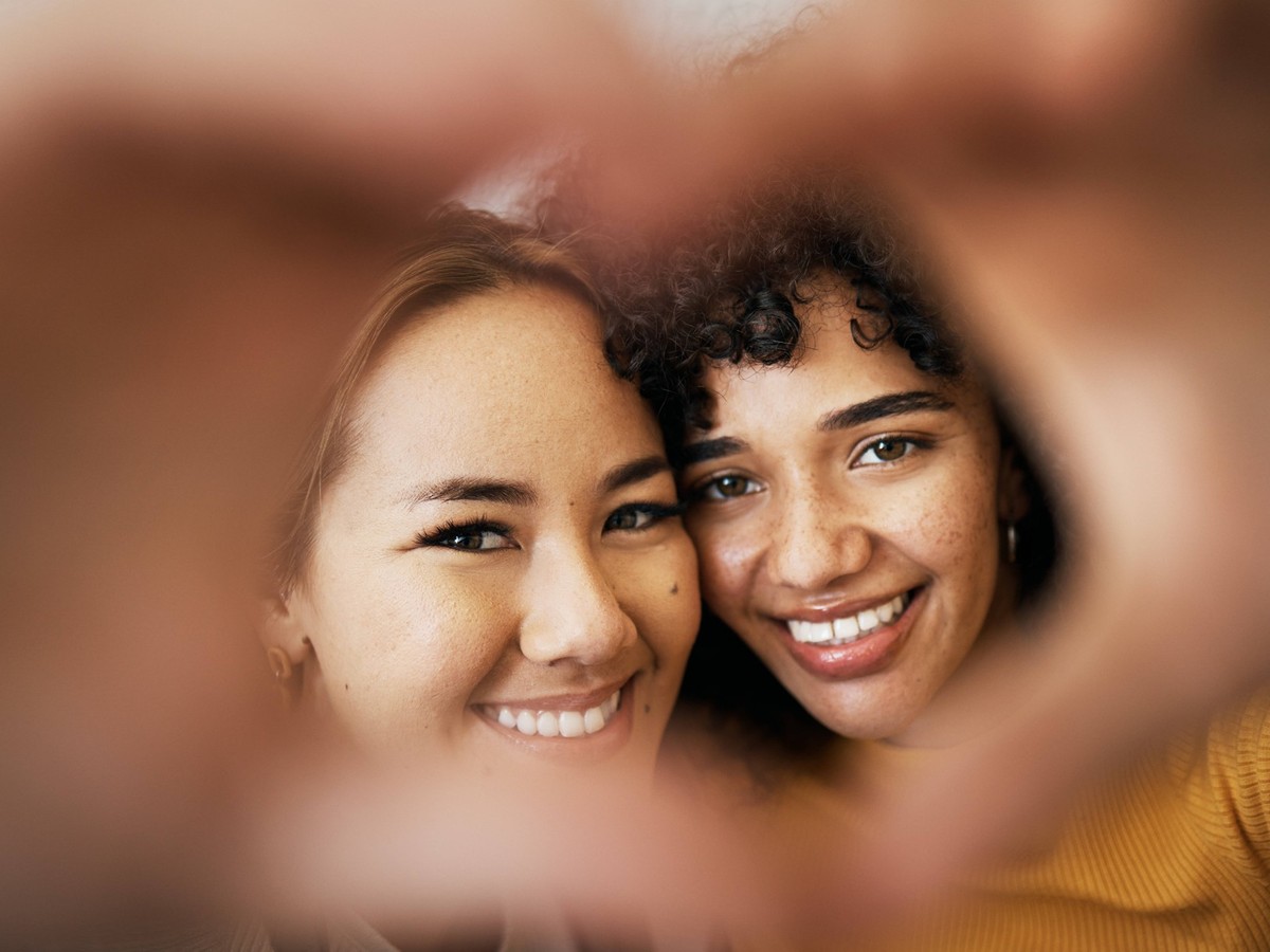 Lesbian couple, smile and heart with hands, portrait and closeup for romance, bonding and love and support for relationship. Happy people, together and solidarity for pride, lgbtq and hope for peace. ...
