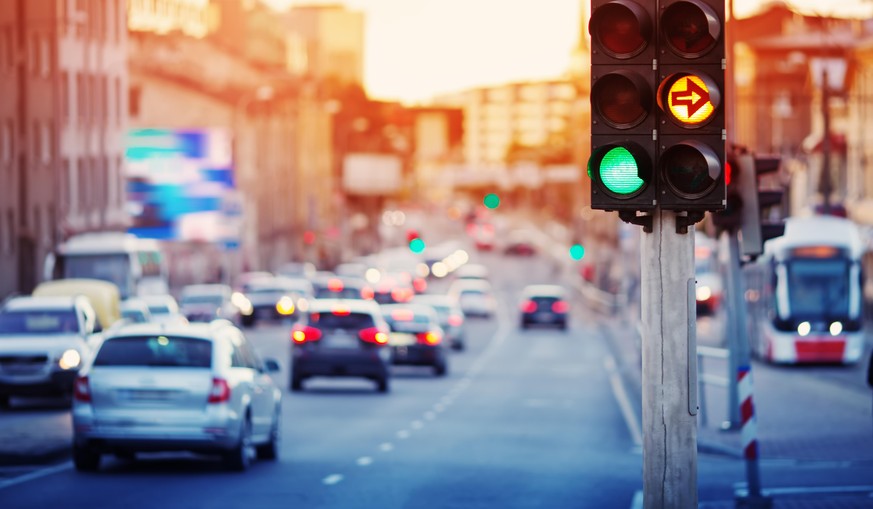 Cars moving on the road in city in late evening. View to the traffic with trafficlights and transport