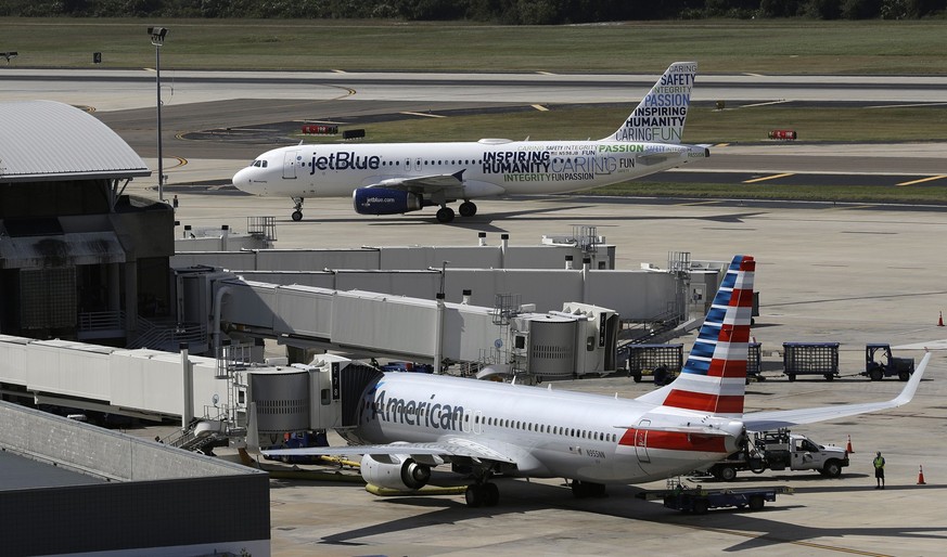 FILE - A JetBlue Airbus A320 taxis to a gate, Oct. 26, 2016, after landing, as an American Airlines jet is seen parked at its gate at Tampa International Airport in Tampa, Fla. On Monday, June 12, 202 ...