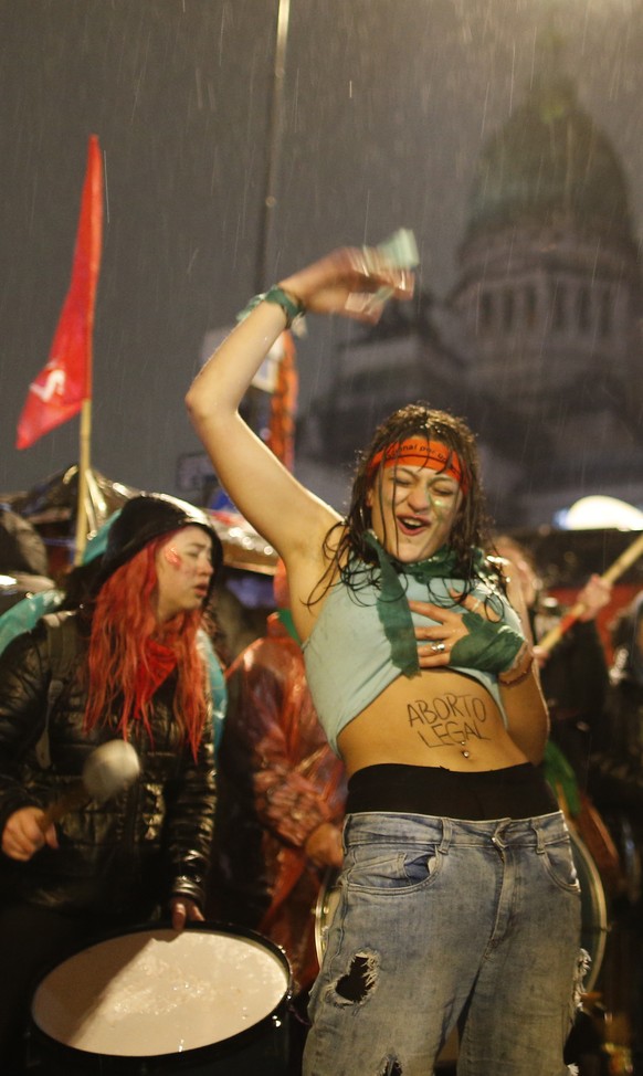A women in support of decriminalizing abortion shows the Spanish message &quot;Legal abortion&quot; on her stomach as she gathers with others in the rain outside Congress where lawmakers are debating  ...